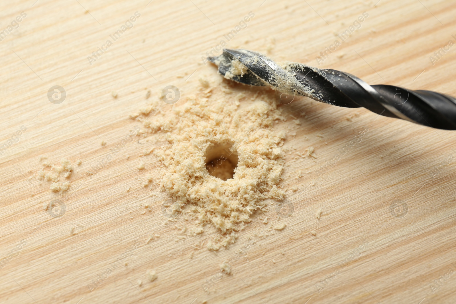 Photo of Drill bit and sawdust on holed wooden surface, closeup