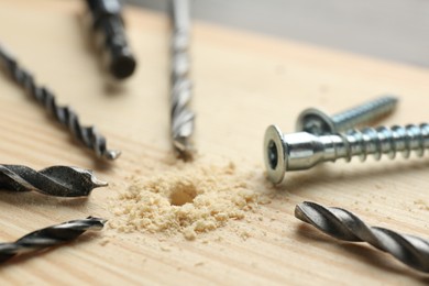 Photo of Different drill bits on holed wooden surface, closeup