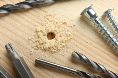 Different drill bits on holed wooden surface, closeup