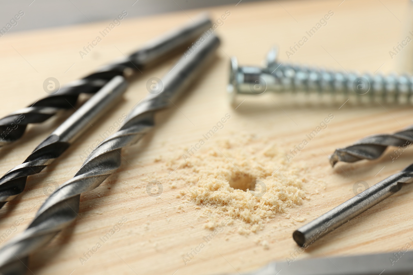 Photo of Different drill bits on holed wooden surface, closeup