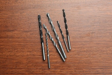 Photo of Many drill bits on wooden table, flat lay