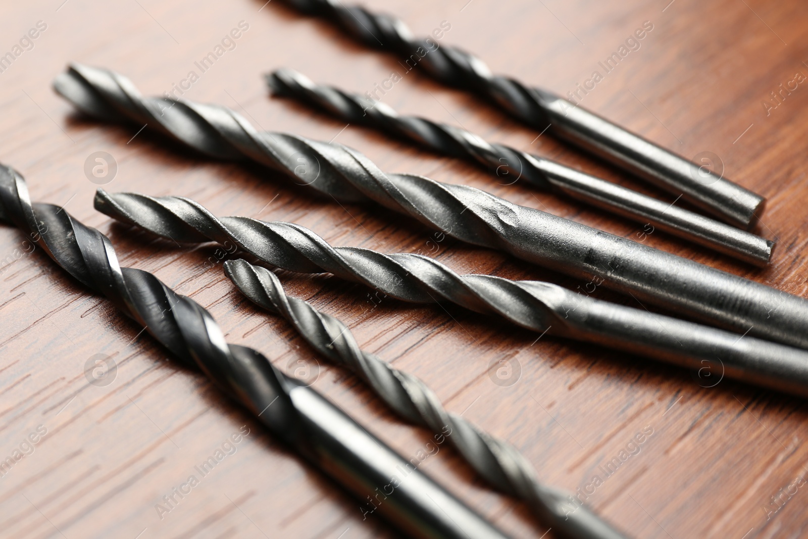 Photo of Many drill bits on wooden table, closeup