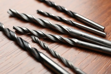 Photo of Many drill bits on wooden table, closeup