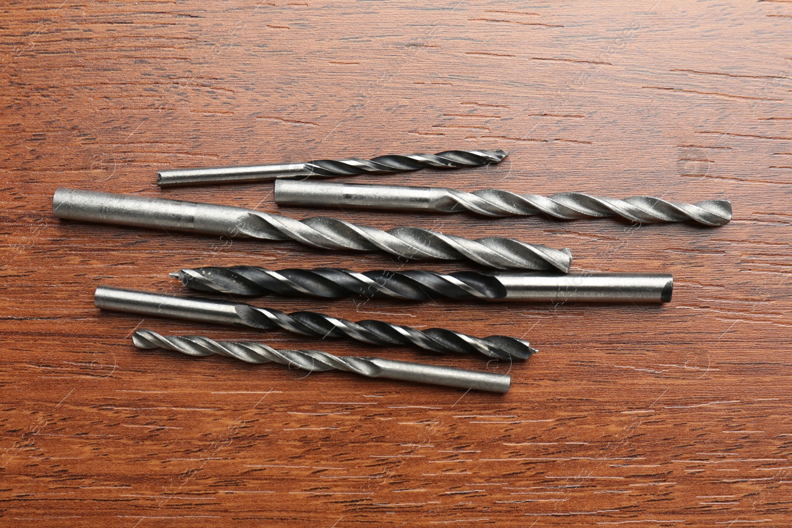 Photo of Many drill bits on wooden table, flat lay