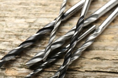 Photo of Many drill bits on wooden table, closeup