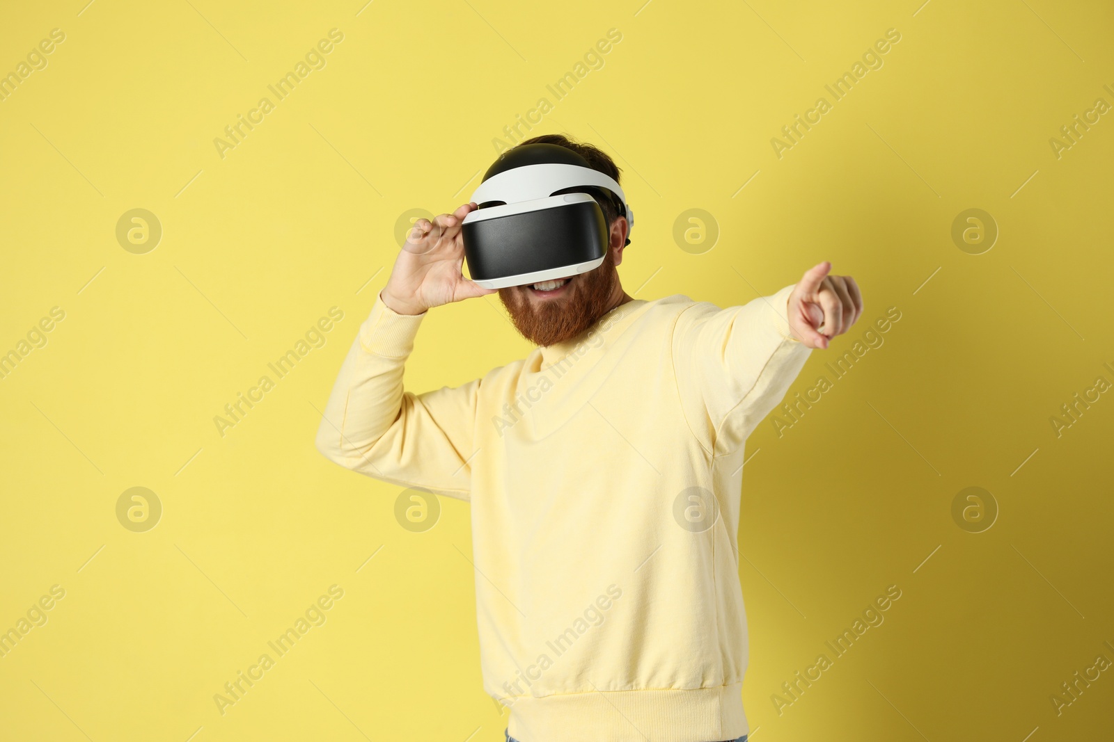 Photo of Man using virtual reality headset on pale yellow background