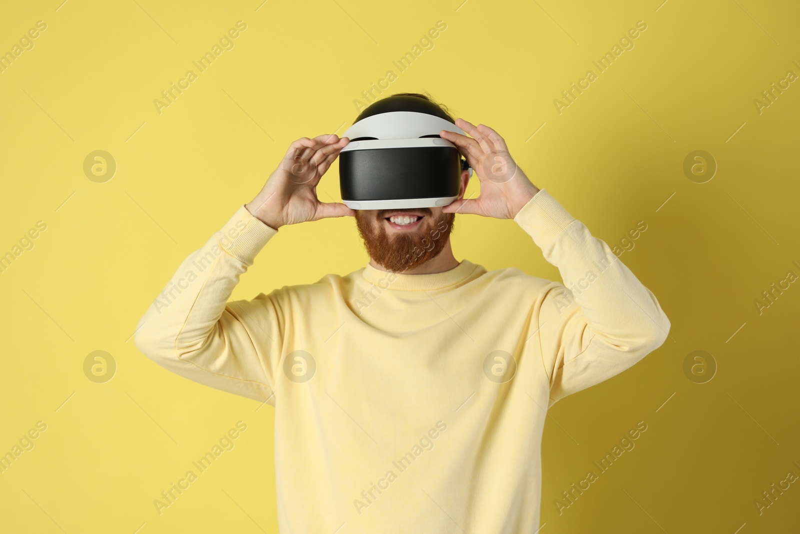 Photo of Man using virtual reality headset on pale yellow background