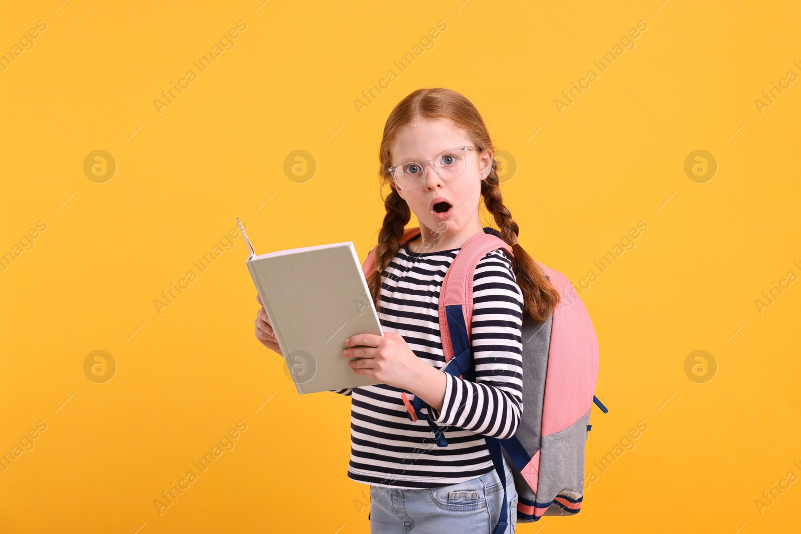 Photo of Surprised girl with book on yellow background