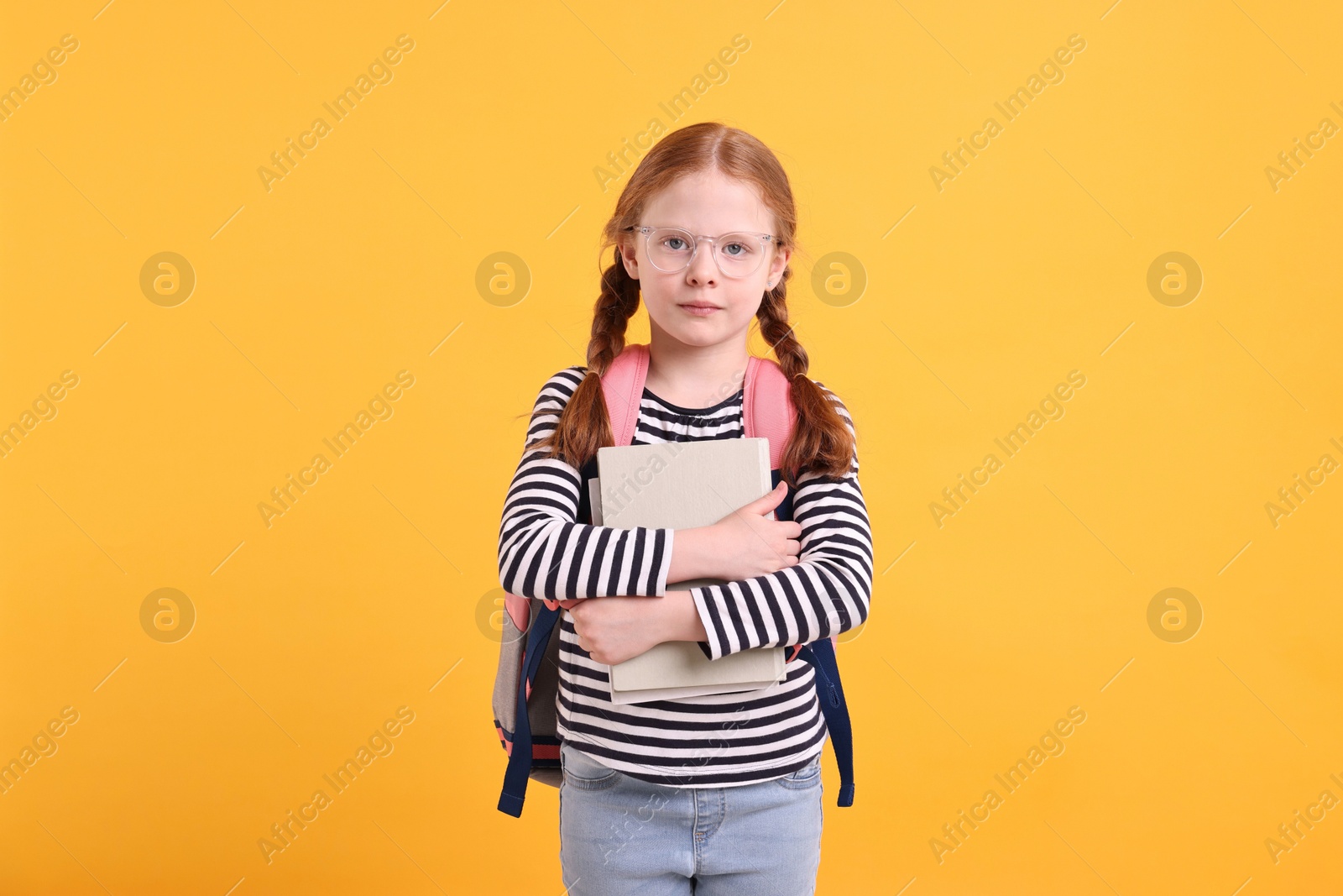 Photo of Cute little girl with book on yellow background