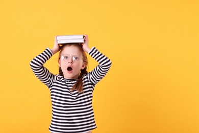 Photo of Surprised girl with books on yellow background. Space for text