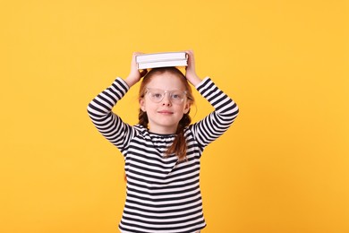 Photo of Cute little girl with book on yellow background
