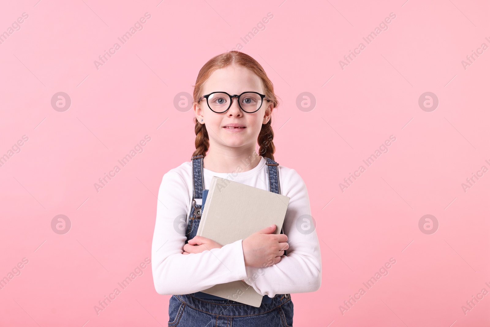 Photo of Cute little girl with book on pink background