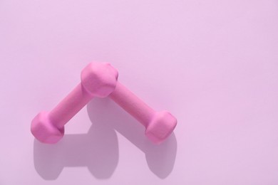 Photo of Two dumbbells on violet background, top view. Space for text