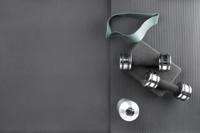 Photo of Dumbbells, yoga block, mat, thermo bottle and fitness elastic band on black background, flat lay. Space for text