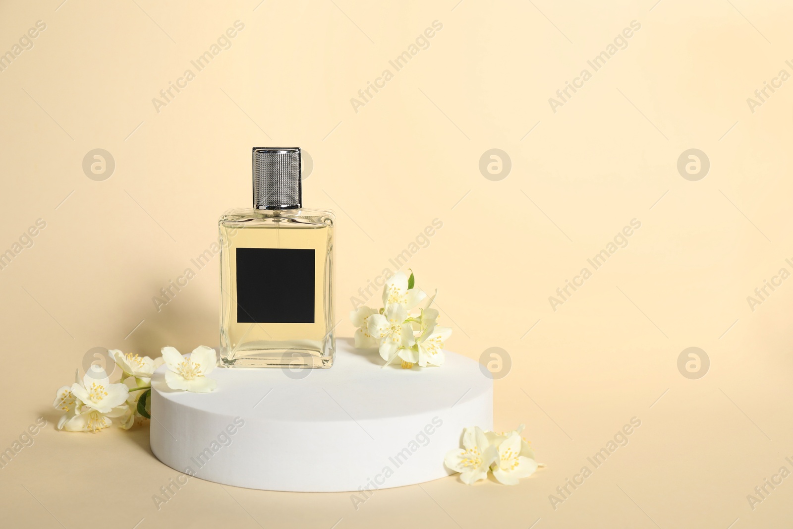 Photo of Presentation of aromatic perfume in bottle and beautiful jasmine flowers against beige background, space for text