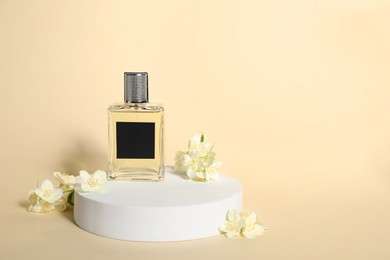 Photo of Presentation of aromatic perfume in bottle and beautiful jasmine flowers against beige background, space for text