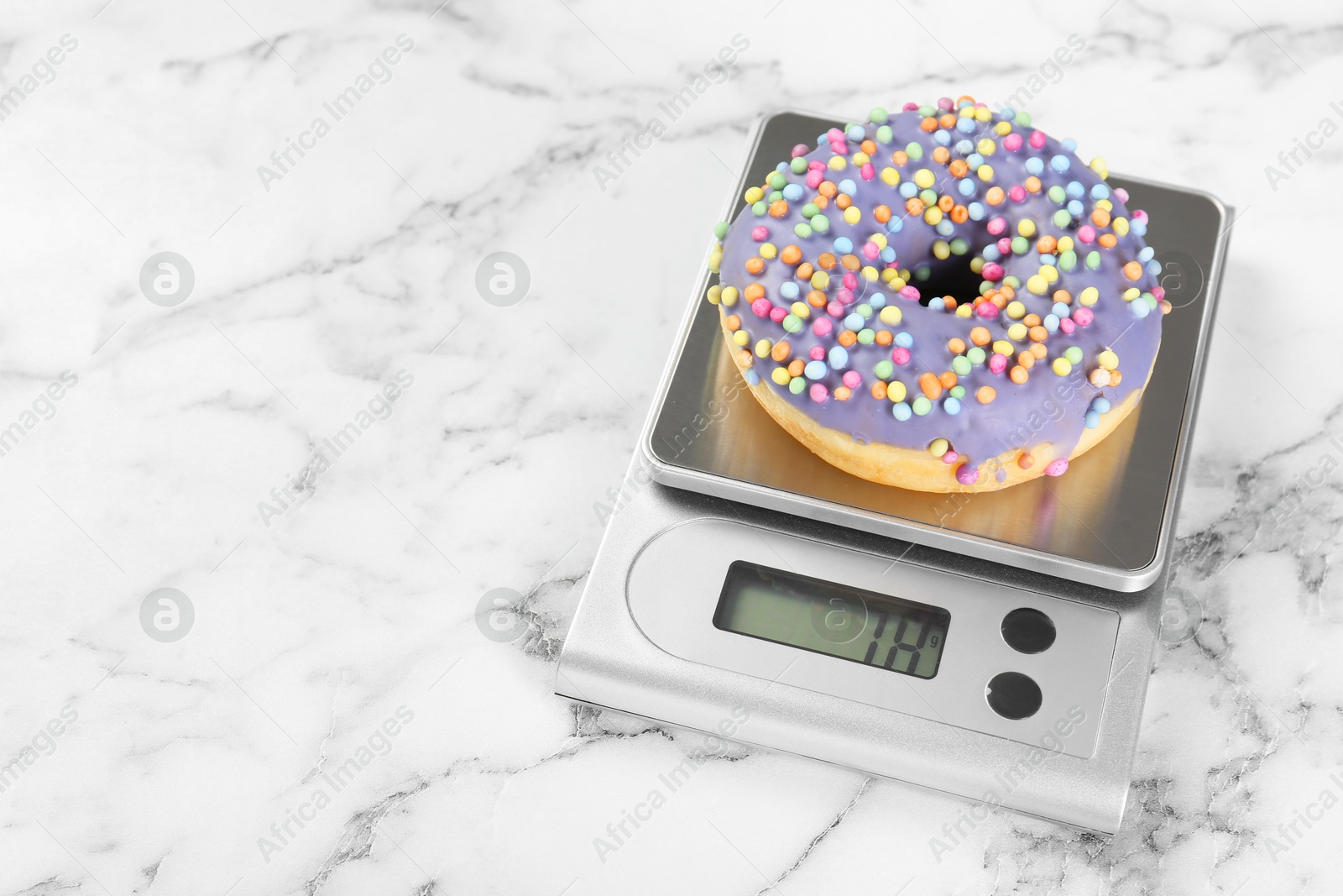 Photo of Kitchen scale with donut on white marble table. Space for text