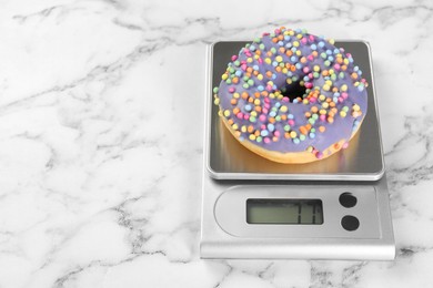 Photo of Kitchen scale with donut on white marble table. Space for text