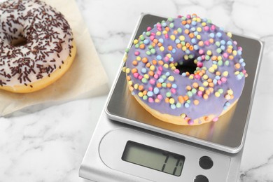 Kitchen scale with donut on white marble table, closeup