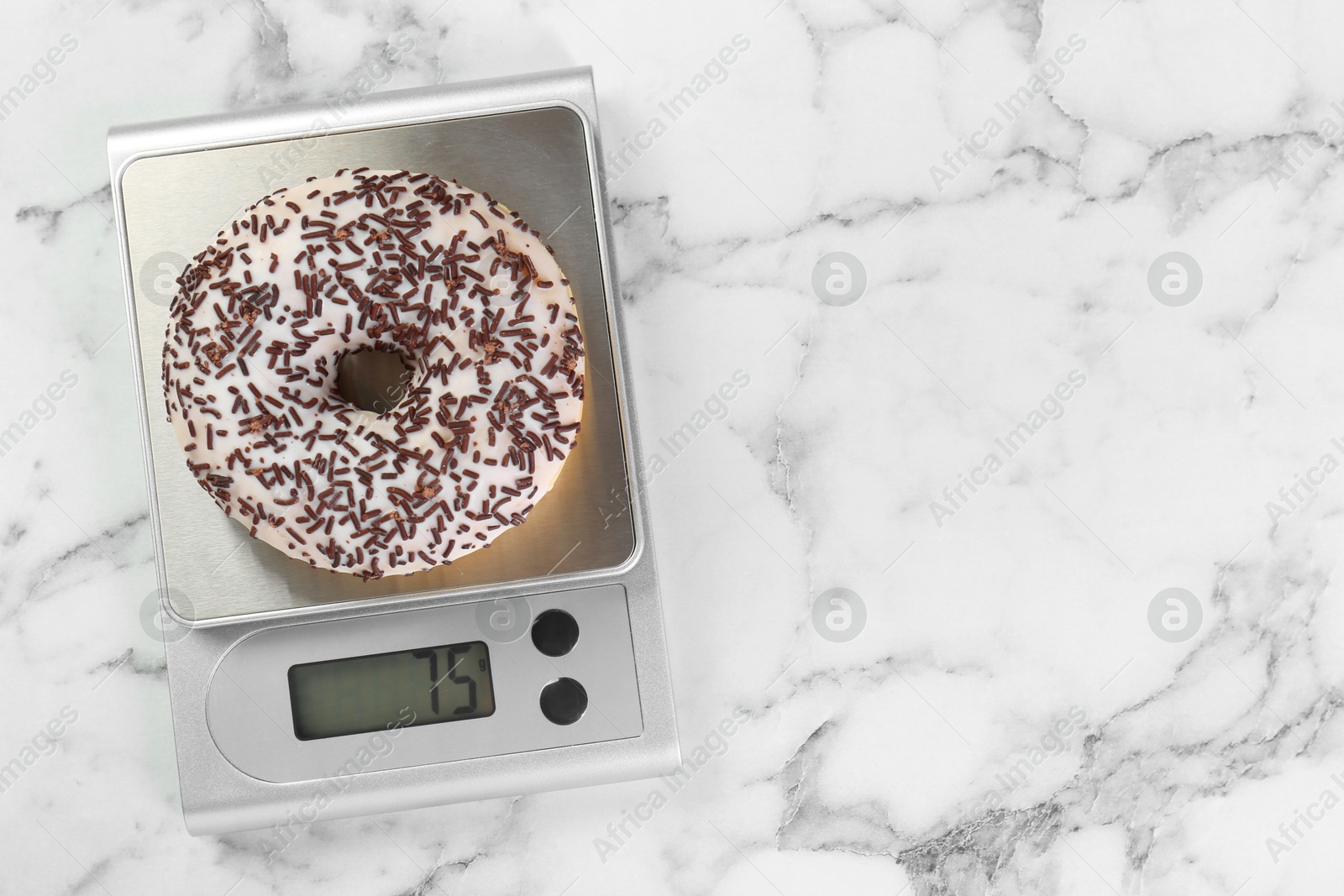 Photo of Kitchen scale with donut on white marble table, top view. Space for text