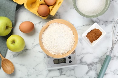 Photo of Flat lay composition of kitchen scale with bowl of flour and products on white marble table