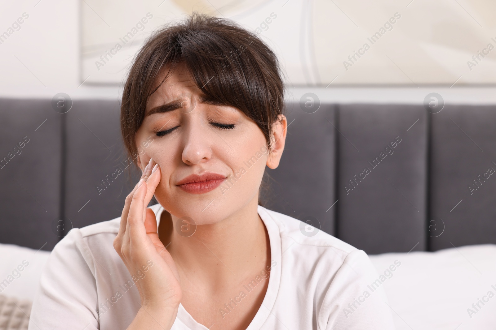 Photo of Upset young woman suffering from toothache indoors