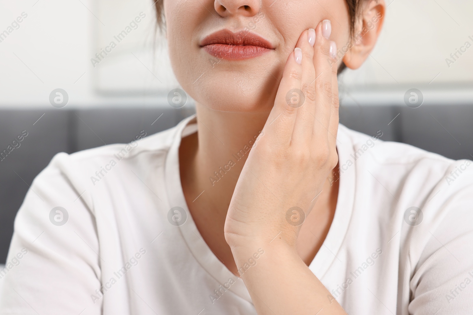 Photo of Woman suffering from toothache indoors, closeup view