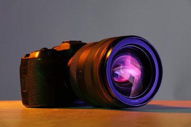 Modern photo camera in neon lights on table