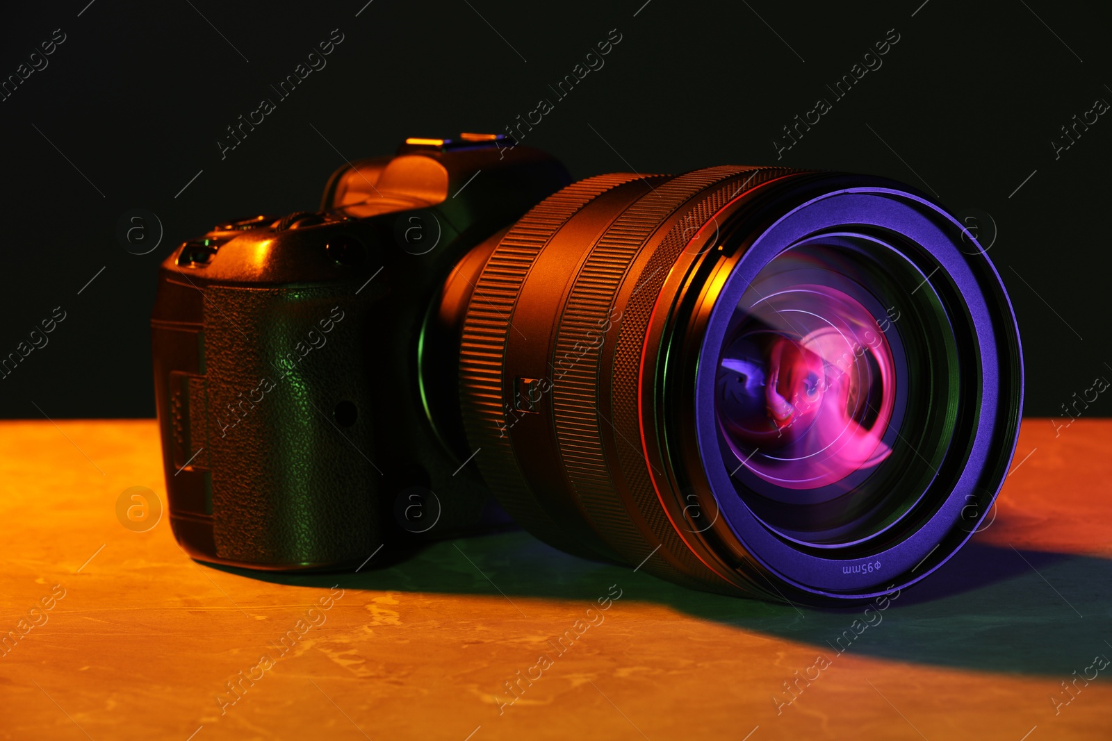 Photo of Modern photo camera in neon lights on table