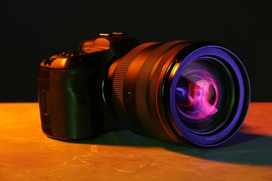 Modern photo camera in neon lights on table