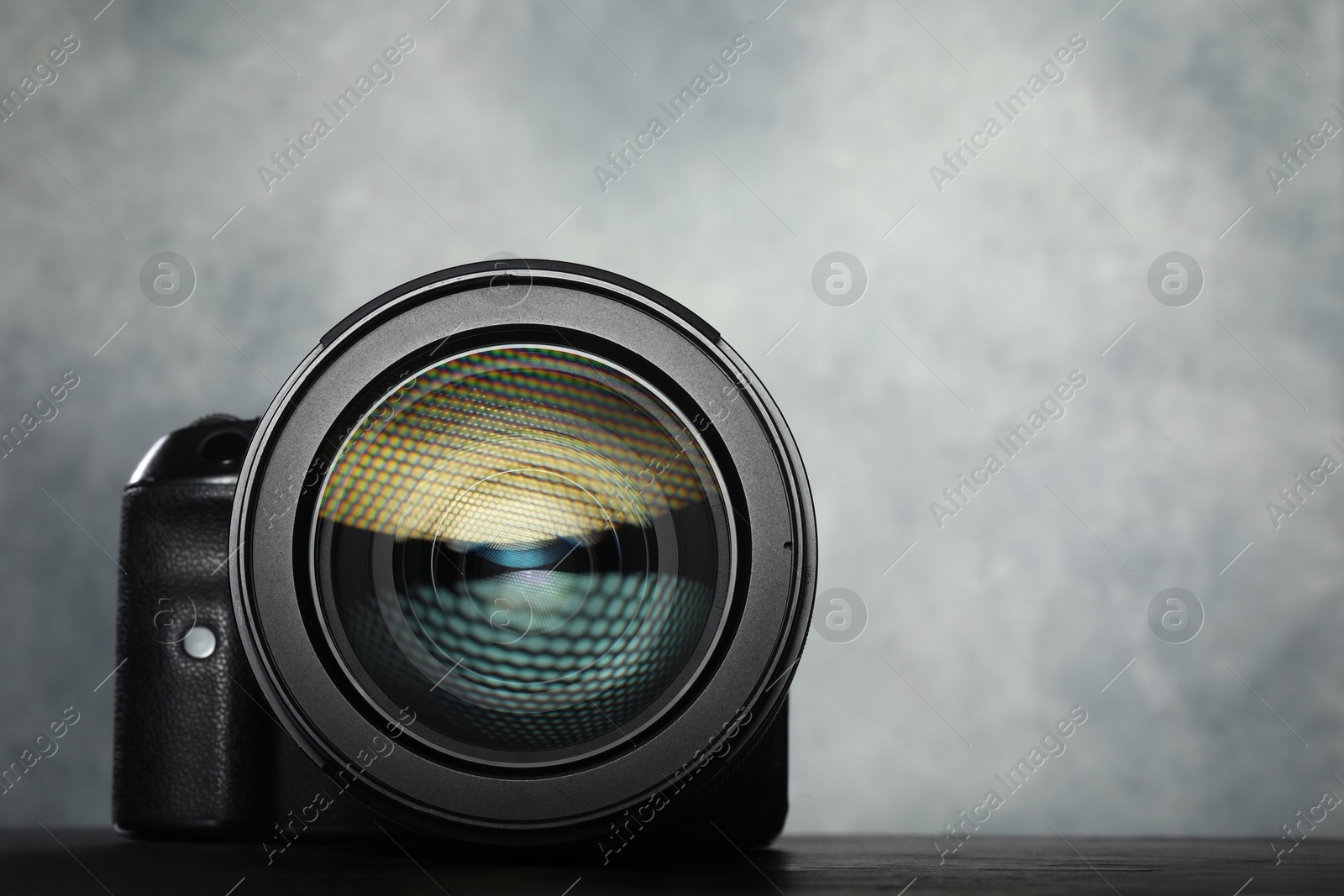 Photo of Modern photo camera on black table, space for text