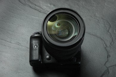 Modern photo camera on black table, above view