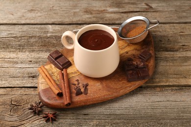 Photo of Tasty melted chocolate in cup and spices on wooden table