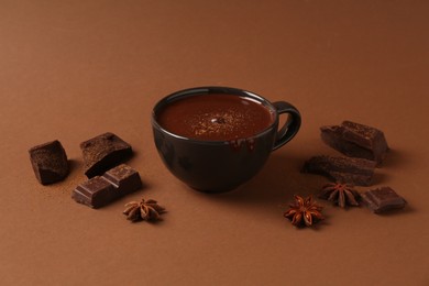 Photo of Tasty melted chocolate in cup and anise stars on brown background