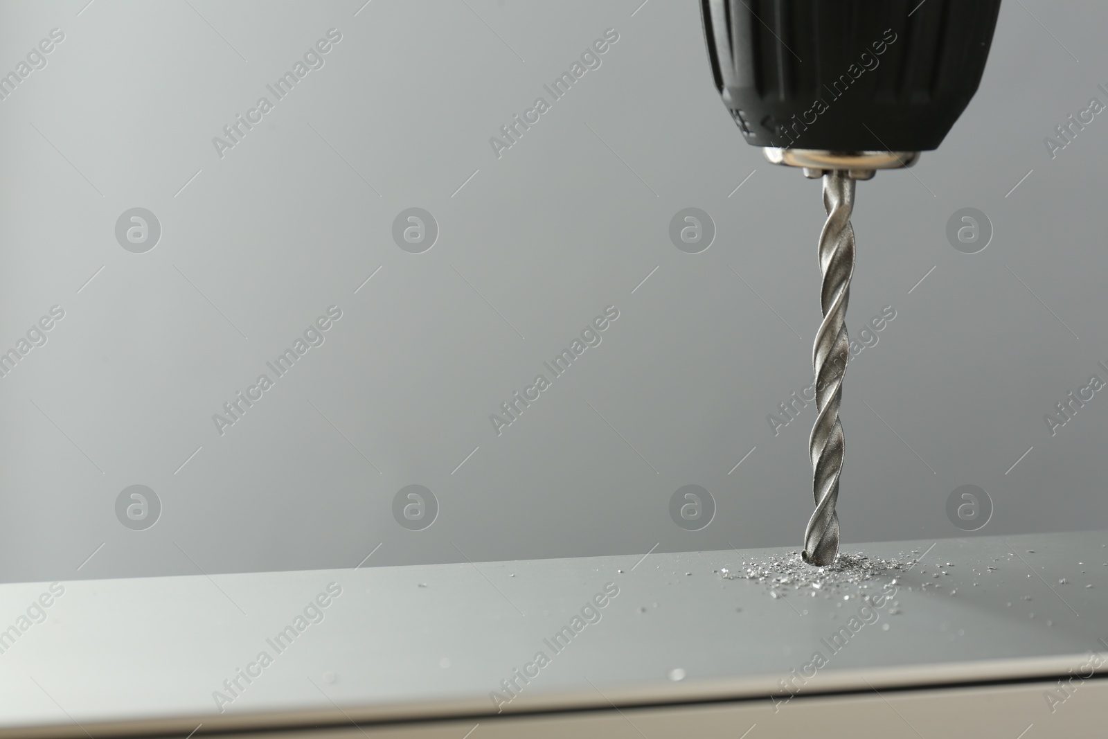 Photo of Drilling hole in light surface on gray background, closeup. Space for text