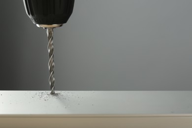 Photo of Drilling hole in light surface on gray background, closeup. Space for text