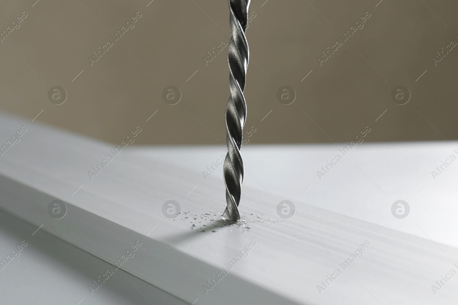 Photo of Drilling hole in plank on table against gray background, closeup