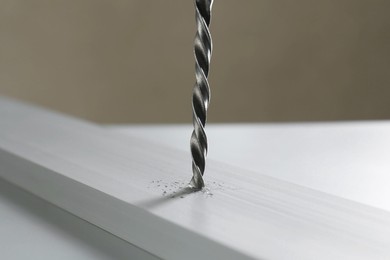 Photo of Drilling hole in plank on table against gray background, closeup