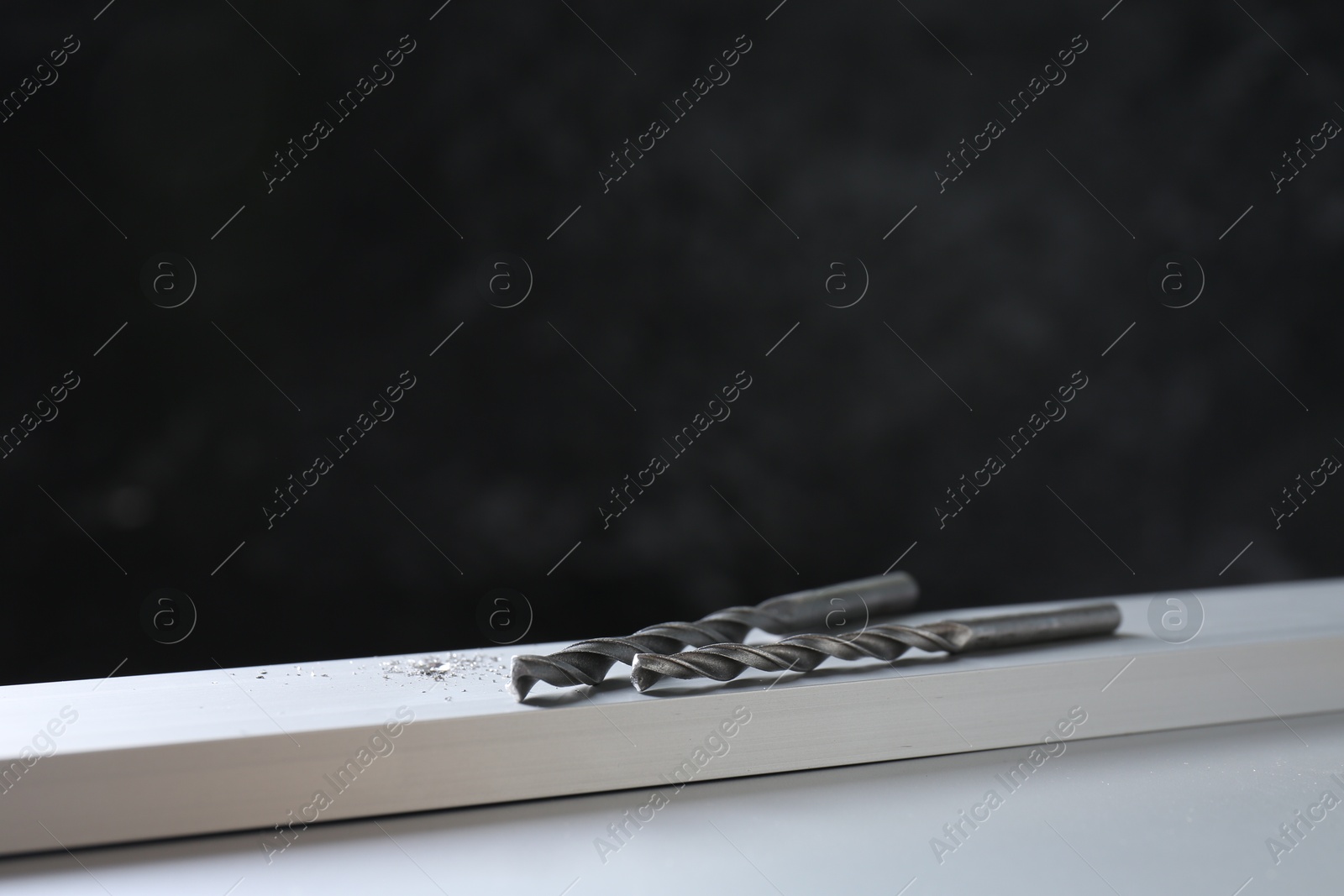 Photo of Bits and plank on white table against black background, space for text