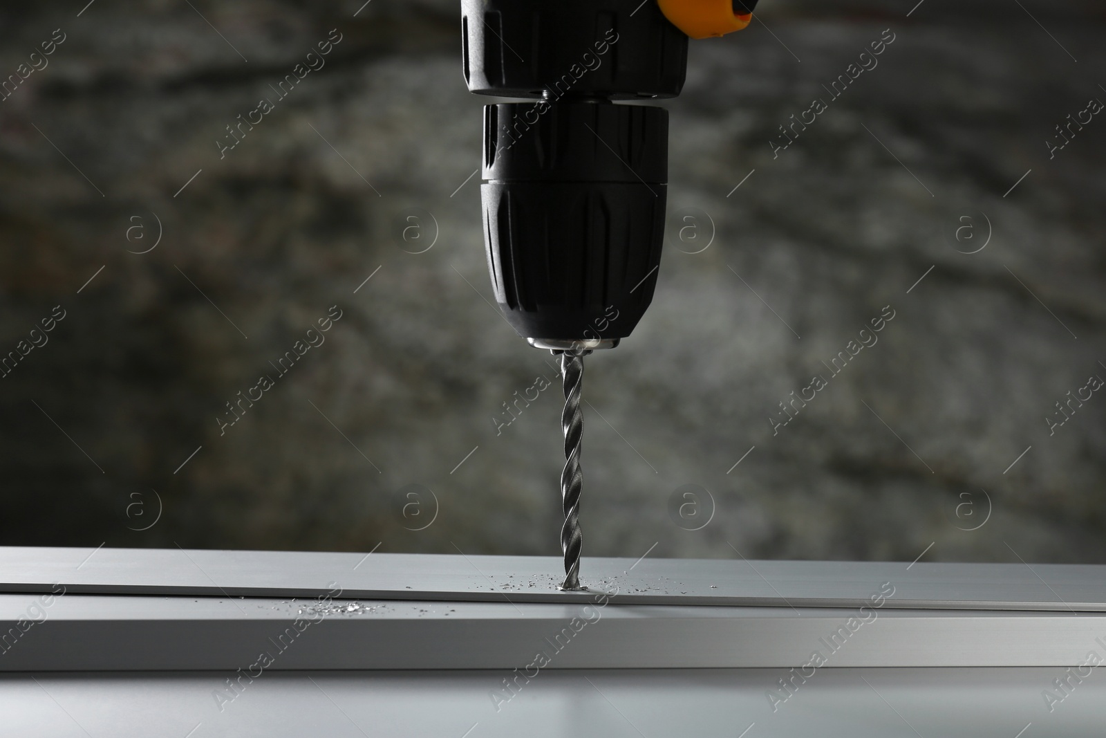 Photo of Drilling hole in plank on table against gray background, closeup