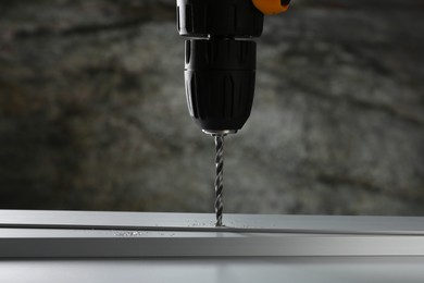 Photo of Drilling hole in plank on table against gray background, closeup