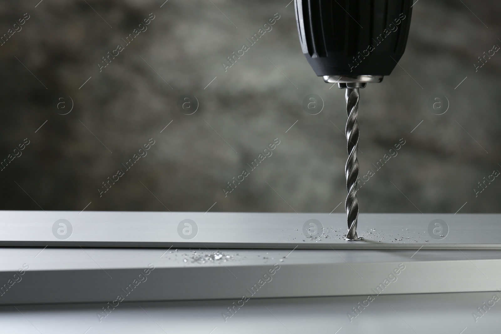 Photo of Drilling hole in plank on table against gray background, closeup. Space for text