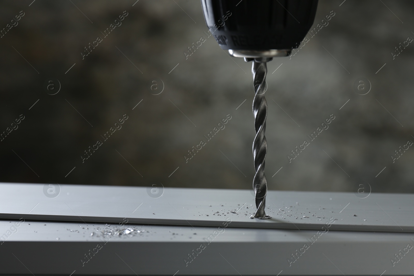 Photo of Drilling hole in plank on table against gray background, closeup