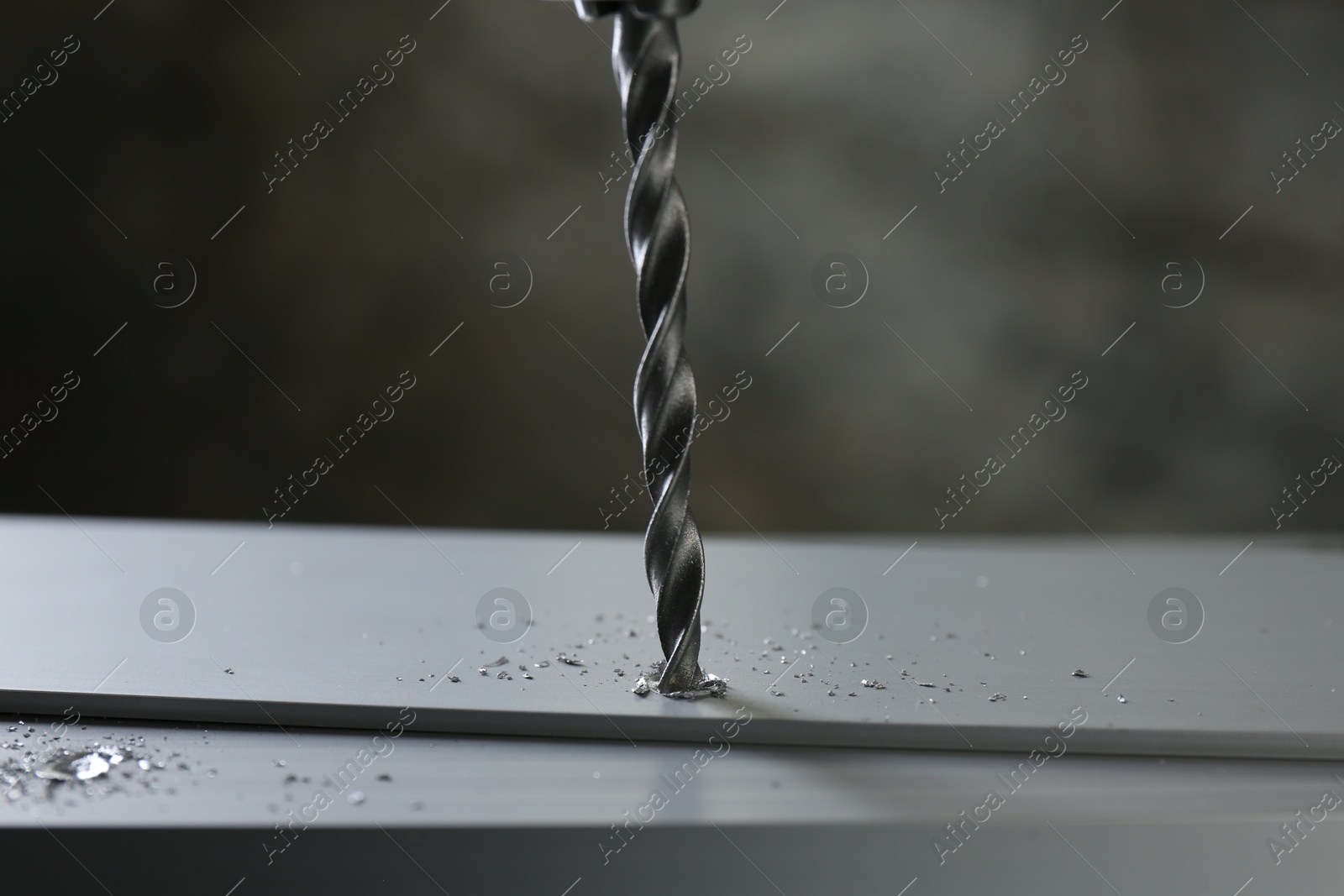 Photo of Drilling hole in plank on table against gray background, closeup