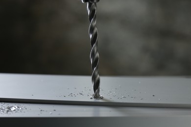 Photo of Drilling hole in plank on table against gray background, closeup