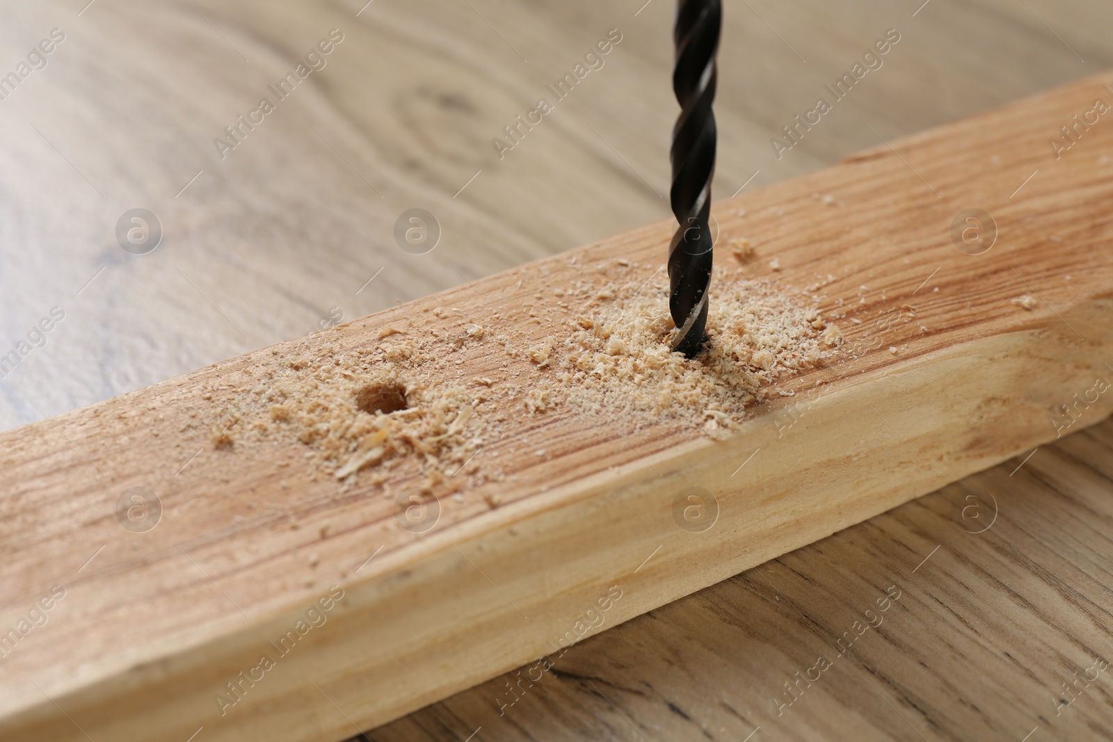 Photo of Drilling hole in plank on wooden table, closeup