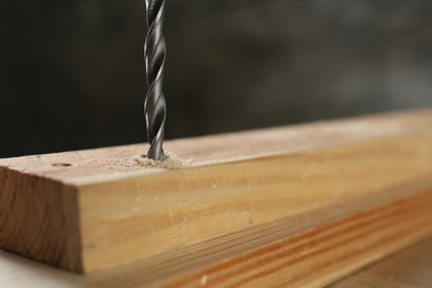 Photo of Drilling hole in wooden plank on table, closeup