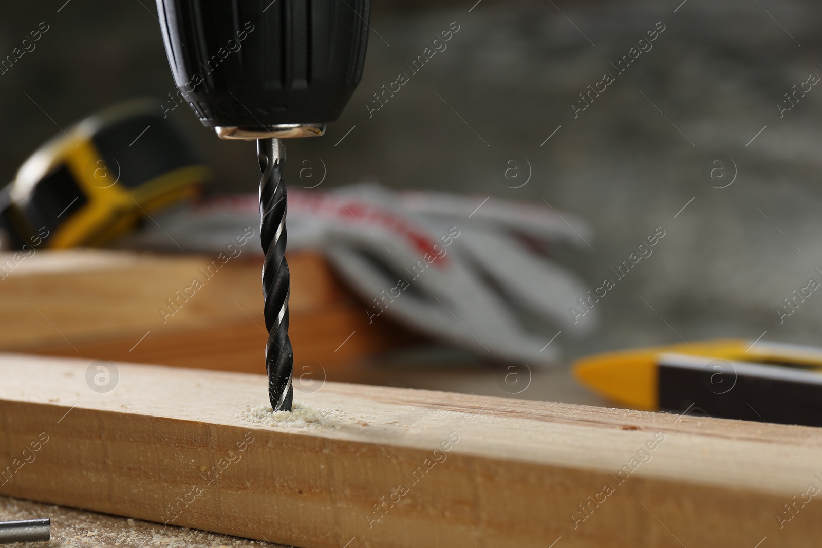 Photo of Drilling hole in wooden plank on table, closeup