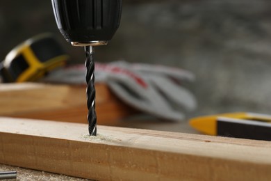 Photo of Drilling hole in wooden plank on table, closeup