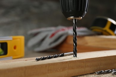 Photo of Drilling hole in wooden plank on table, closeup